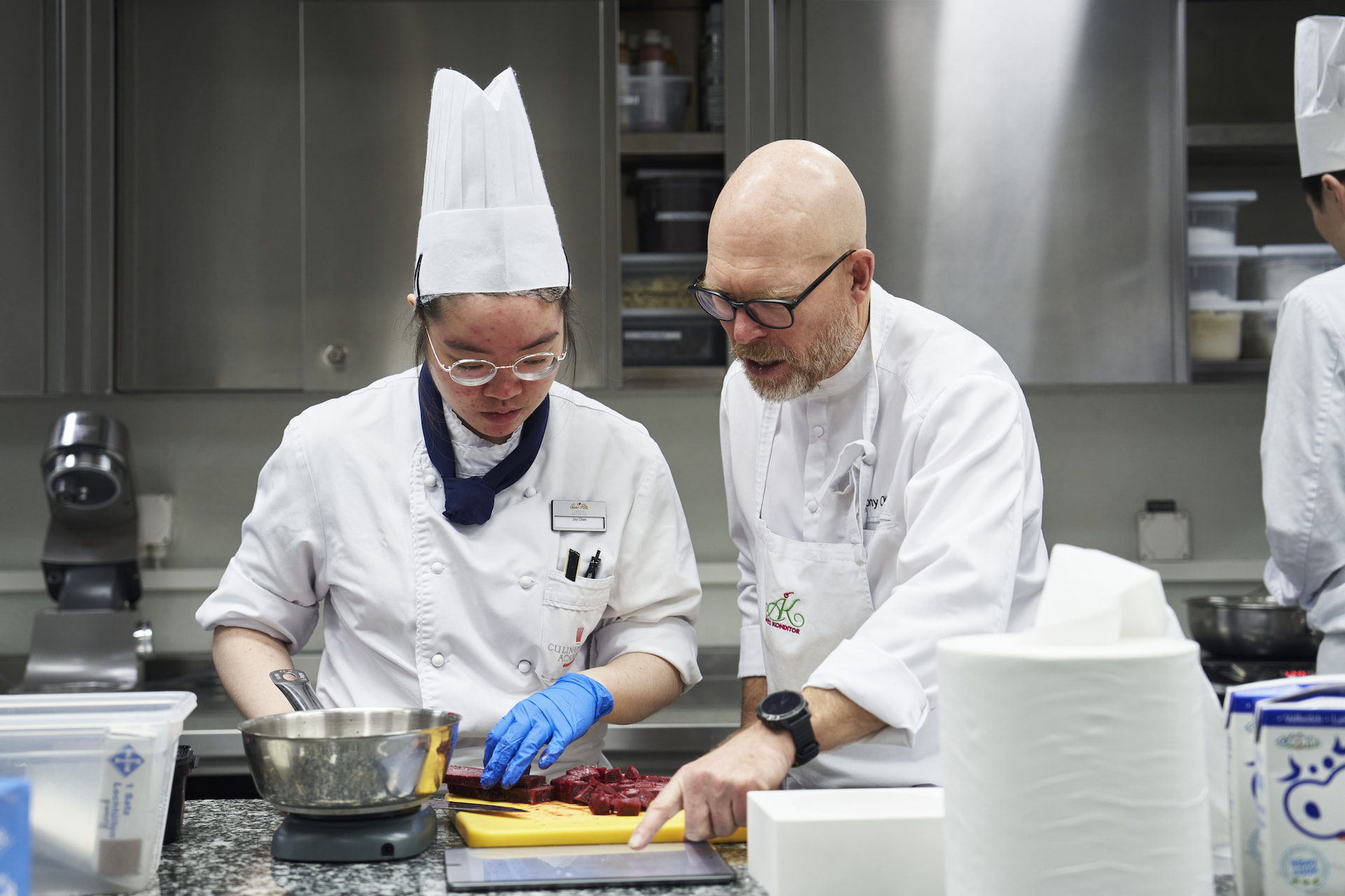 A supervisor teaching a student how to cook.