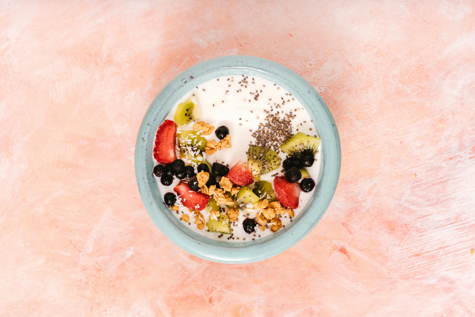 Top view of a bowl of yogurt topped with fruit.