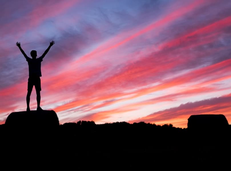 Man reaching the top of a mountain and celebrating